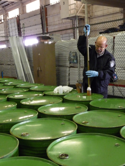 A Customs and Border Patrol agent in a Tacoma, Wash. warehouse draws samples of Chinese honey that is being shipped to Chicago.  (c) Photot by a. schneider